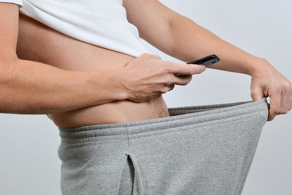 一个男人在裤子下面看着增大的阴茎